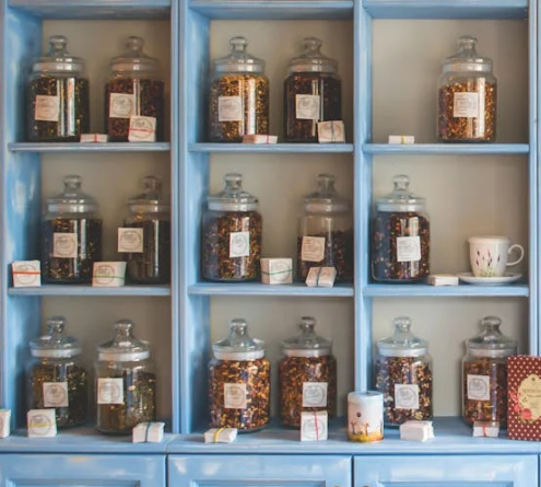 A colorful assortment of jars filled with spices and dry goods neatly arranged on vintage blue kitchen shelves.