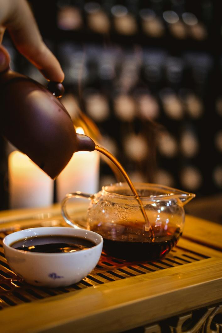 Person pouring a warm brown teacup.