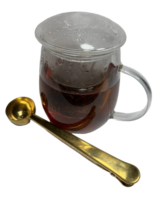 Brewed herbal tea with a golden spoon beside the cup.