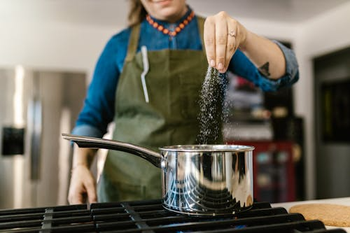 Chef sprinkling salts from Greece into a pan to enhance flavors