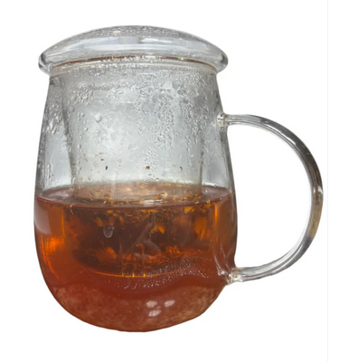  Glass mug of warm amber herbal tea gently brewing, showcasing a calming moment in a creative tea ritual.