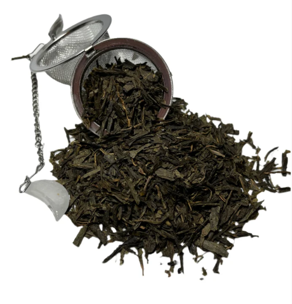 Loose-leaf Earl Grey tea spilling from a stainless-steel infuser onto a white surface.