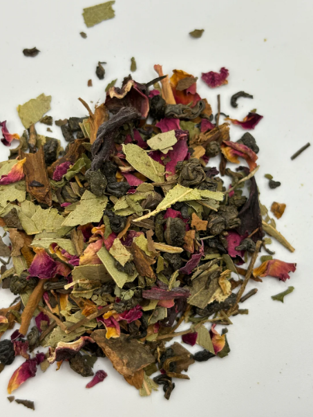 Loose herbal tea blend with mixed leaves, petals, and botanicals on a white background.