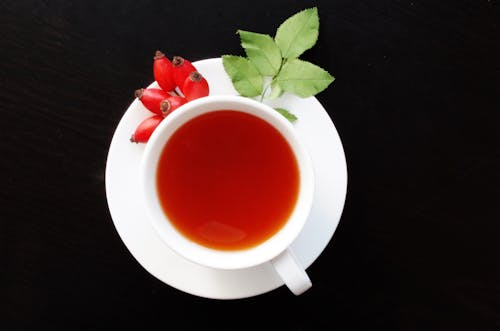 A steaming cup of caffeine-free fruit tea with fresh fruit slices.