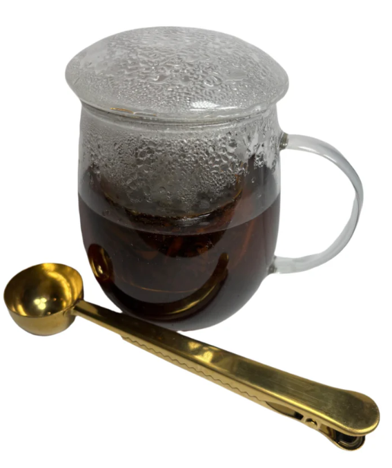 Glass mug of Indian chai masala tea beside a gold teaspoon.