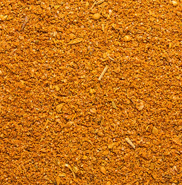 A close-up of a fine golden spice blend with visible herbal specks and powdered seasoning.