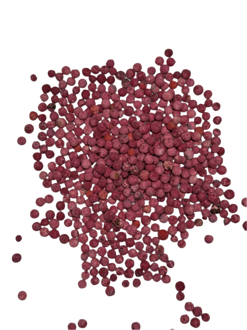 Close-up of loose pink peppercorns scattered on a white background.