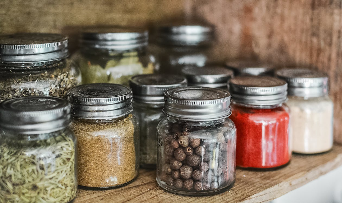 Assorted spice bottles arranged neatly on a kitchen shelf.