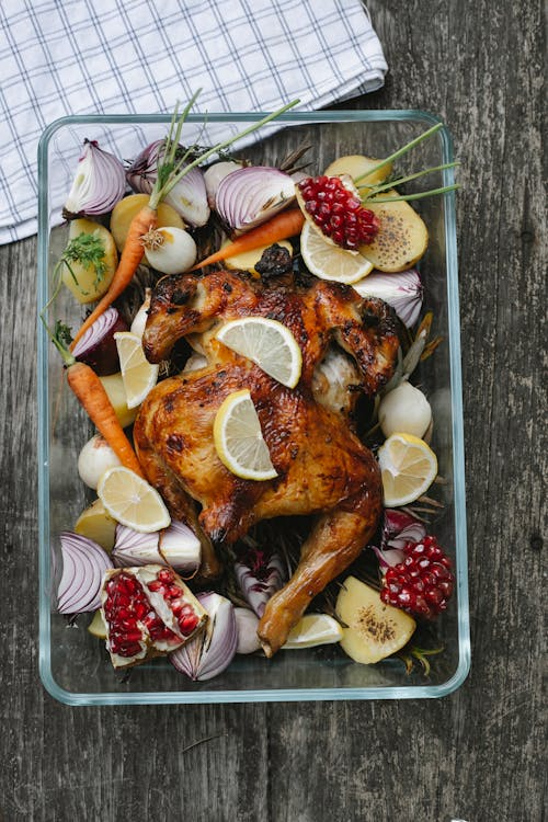 Baked chicken served with a colorful vegetable and fruit mix.