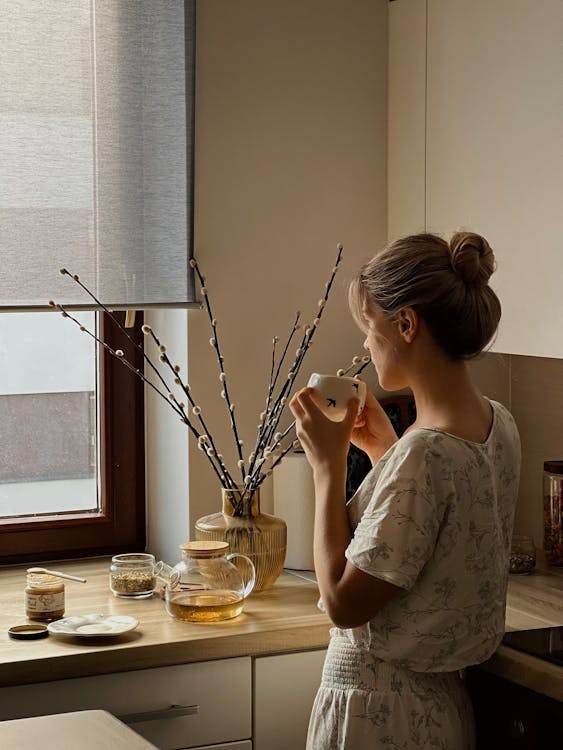 An image of a woman having tea by her window.