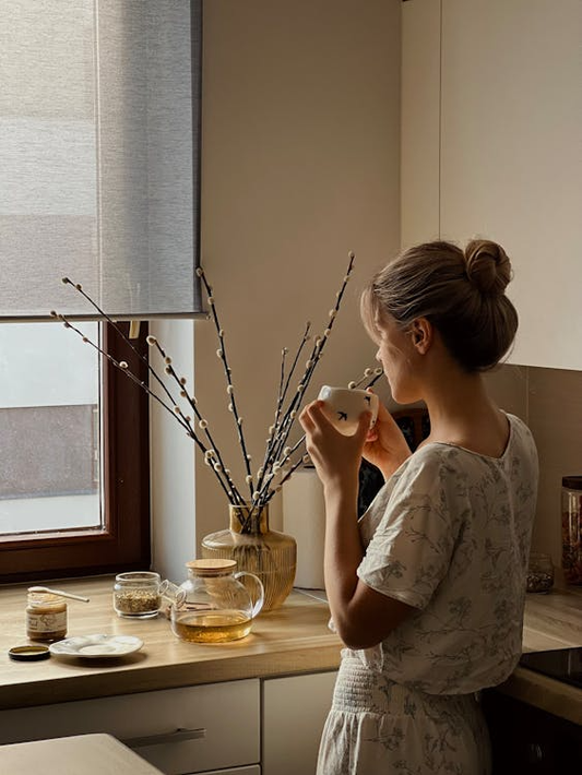 An image of a woman having tea by her window.