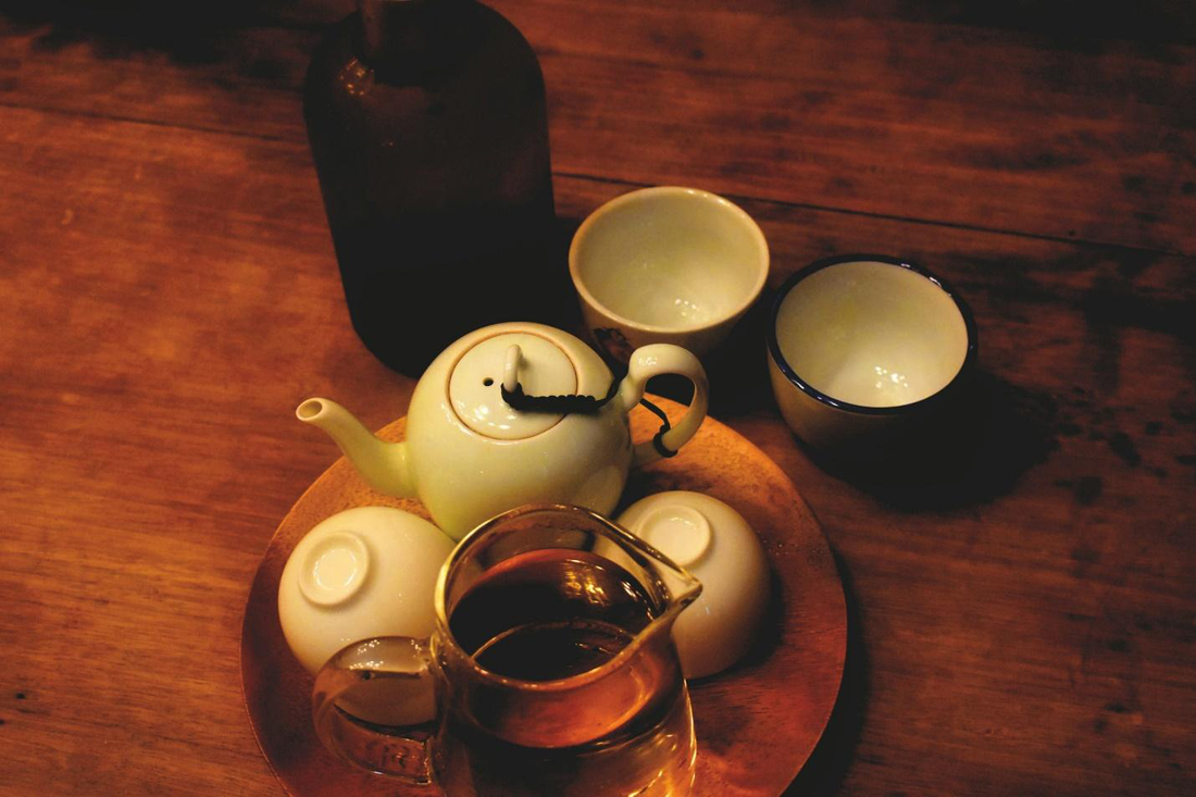 An image of a tea set-up with cups, teapots, and a bottle.
